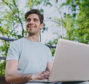 Man ute i park med dator.