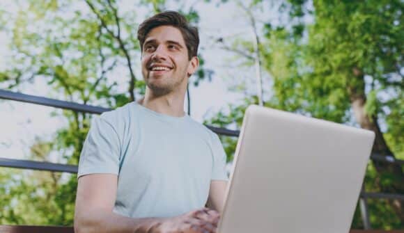 Man ute i park med dator.